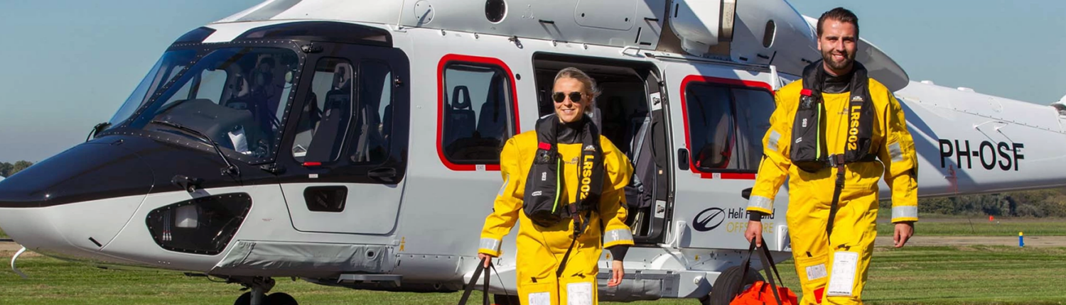 Man en vrouw van bedrijf Biardo Survival Suits stappen uit helicopter in geel pak.